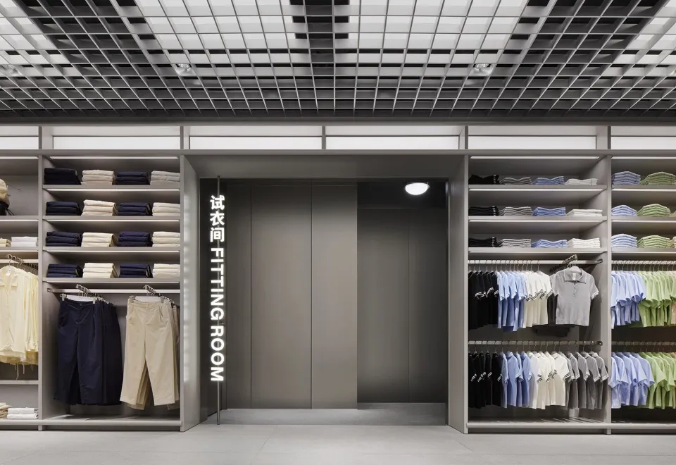 A minimalist clothing store with metallic finishes featuring a fitting room sign.