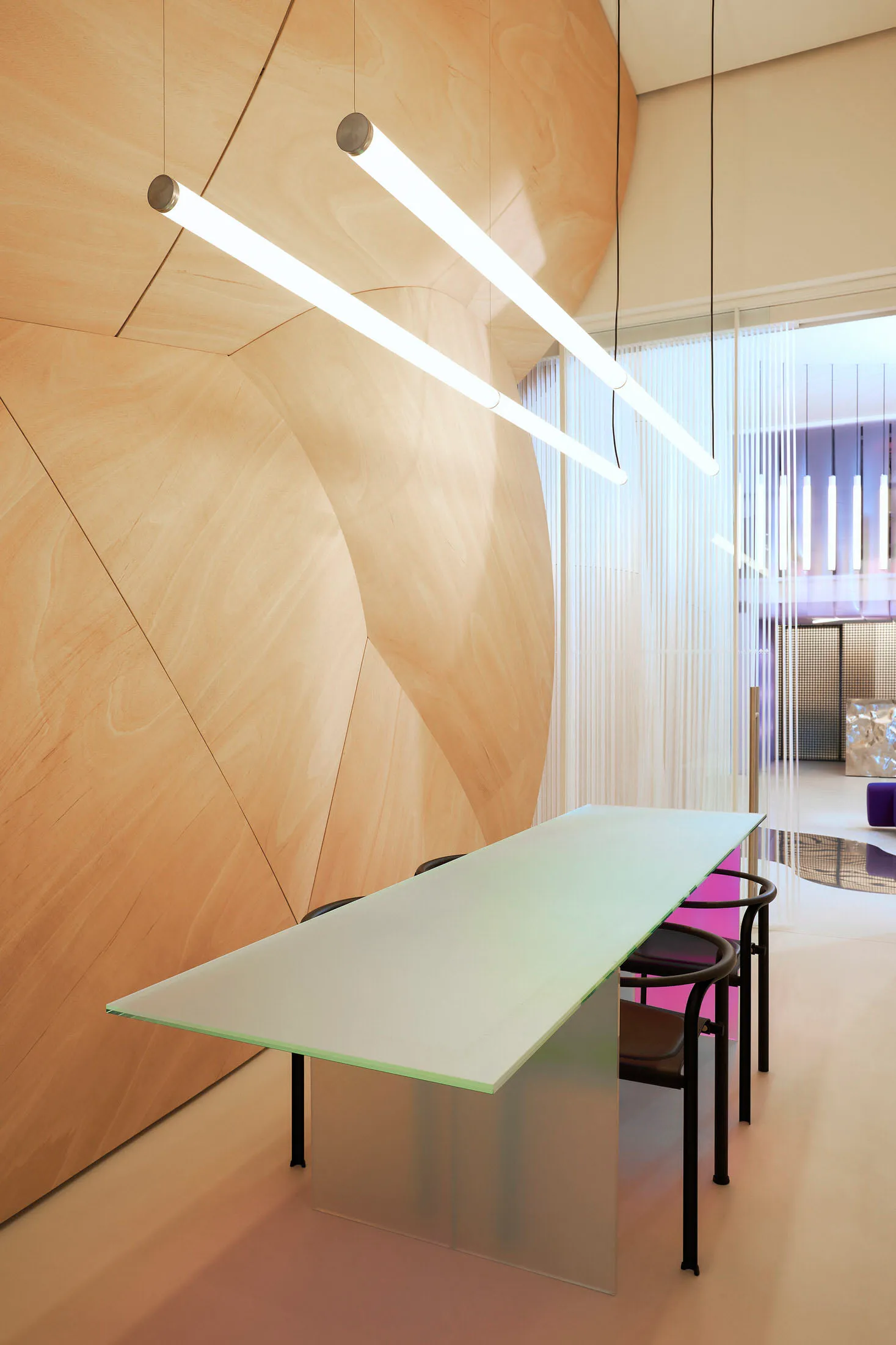 Modern conference room with glass table and minimalist lighting.