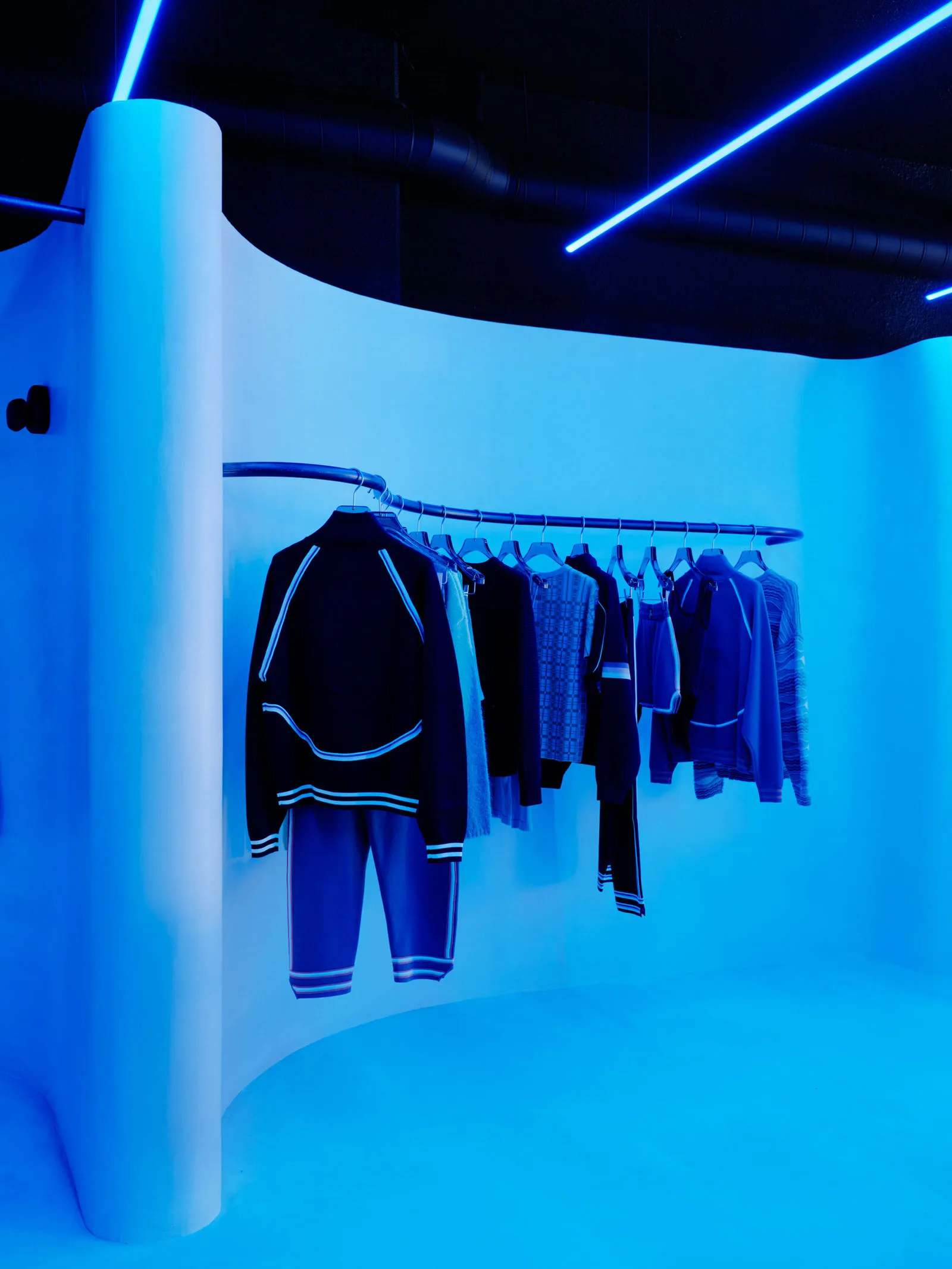 Clothing rack illuminated by blue light in a retail setting