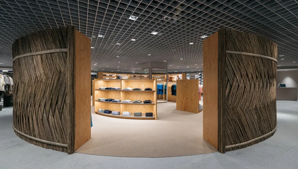 An image of an industrial-themed retail shop showcasing clothing on shelves and racks surrounded by wooden-textured wall pane