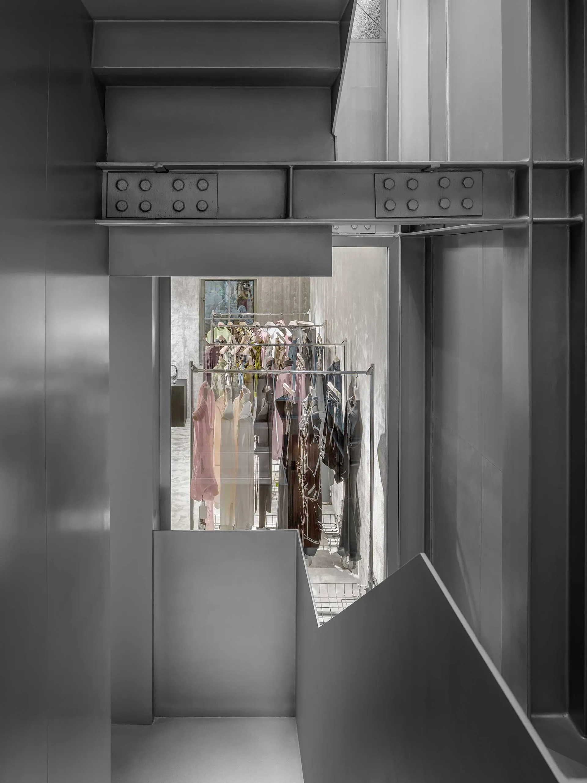 現代服飾店室內,採用深色金屬元素與混凝土牆面。