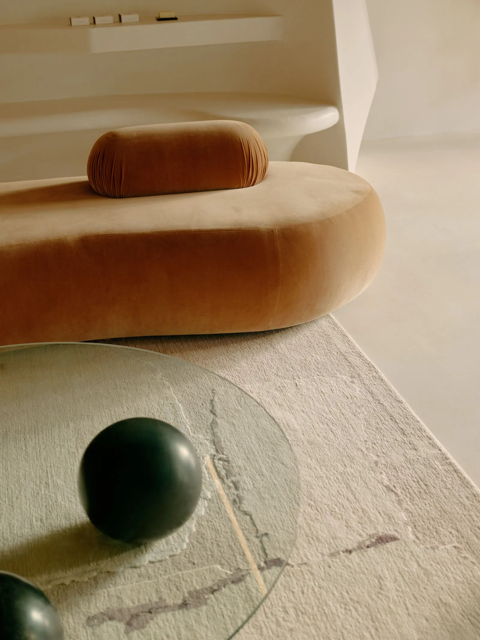 Modern round sofa upholstered in brown velvet with a minimalist living room background.
