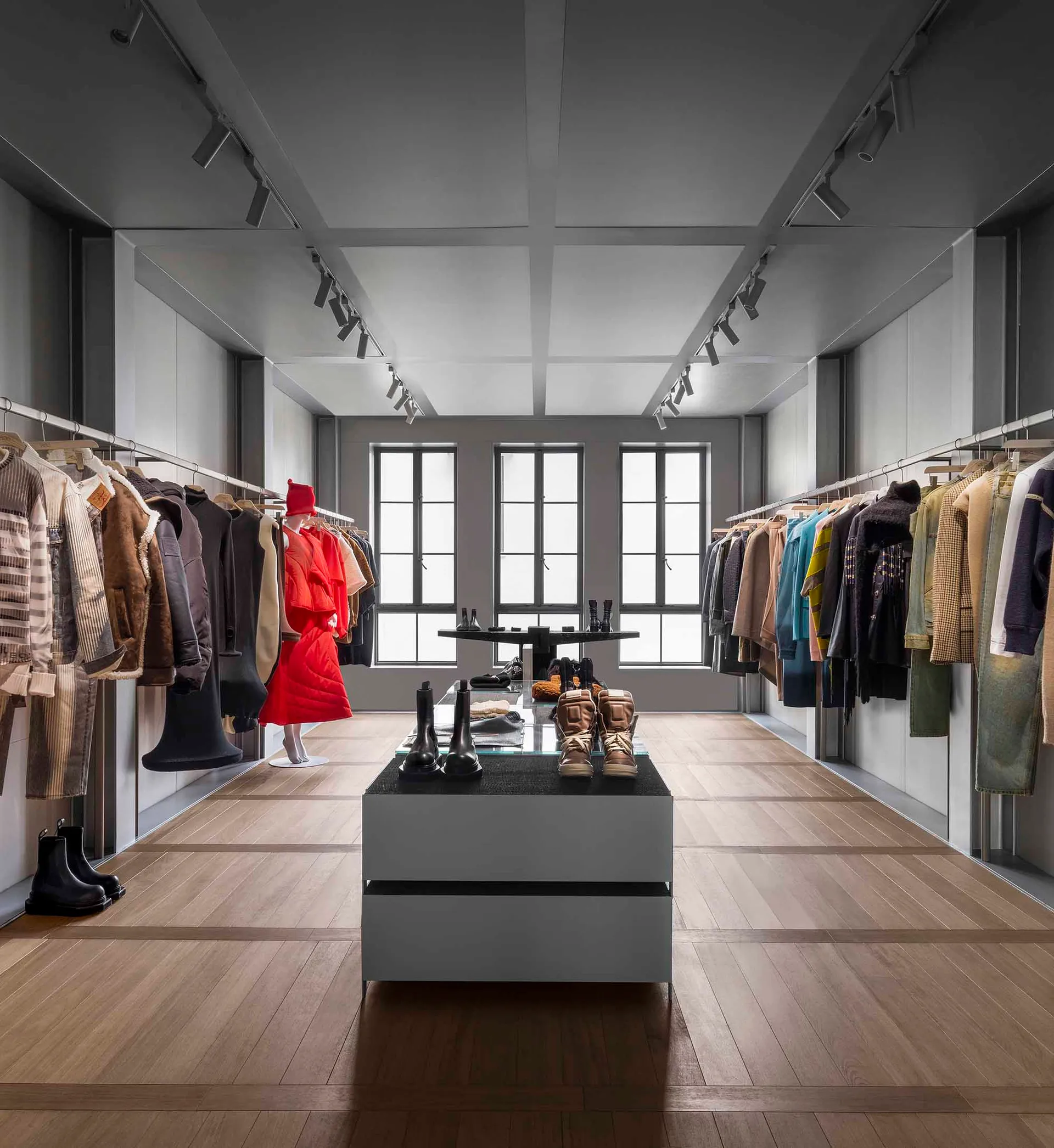 A stylish modern retail clothing store with wooden floors and clothes hanging on racks.