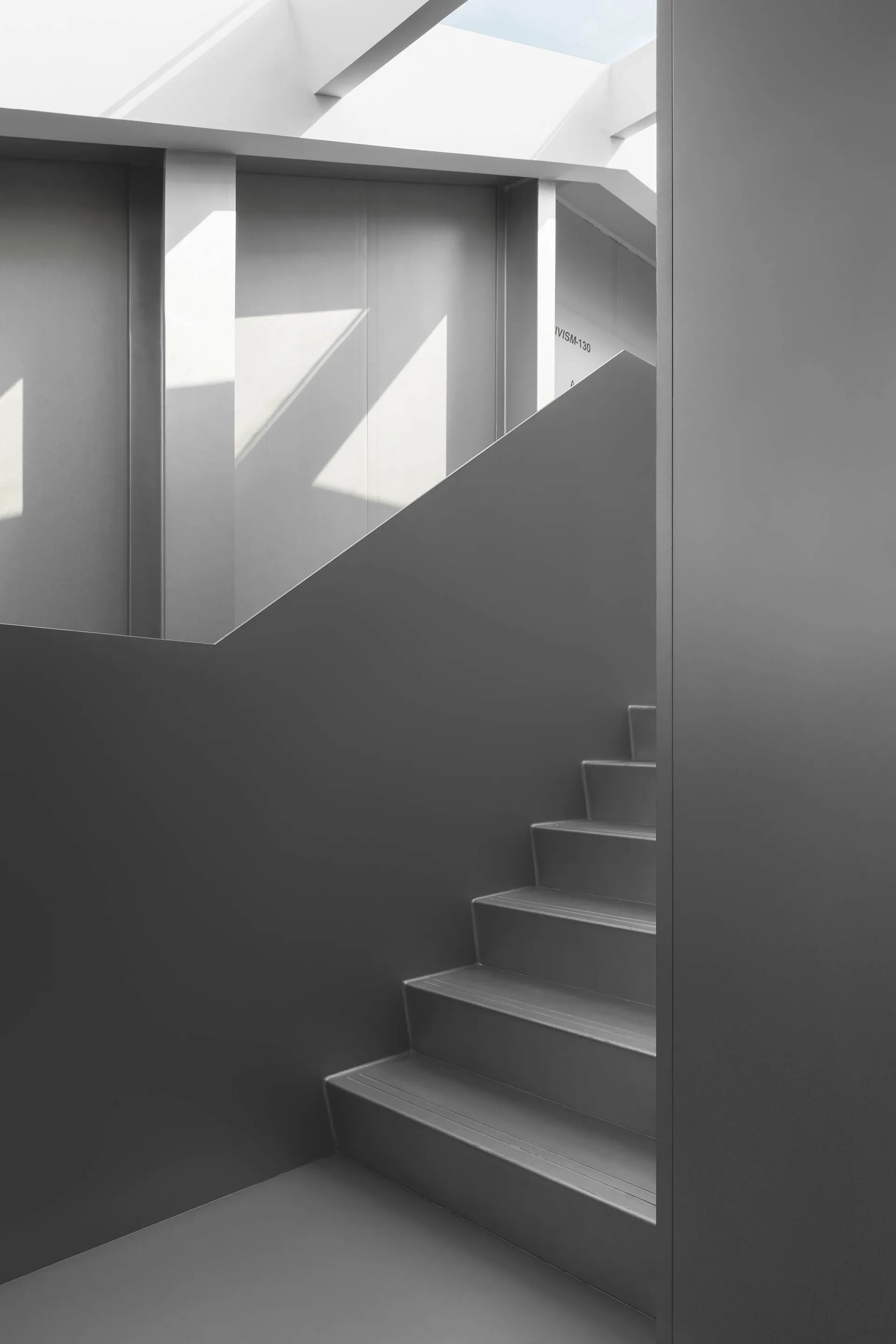 Gray concrete staircase with light shining through a skylight.