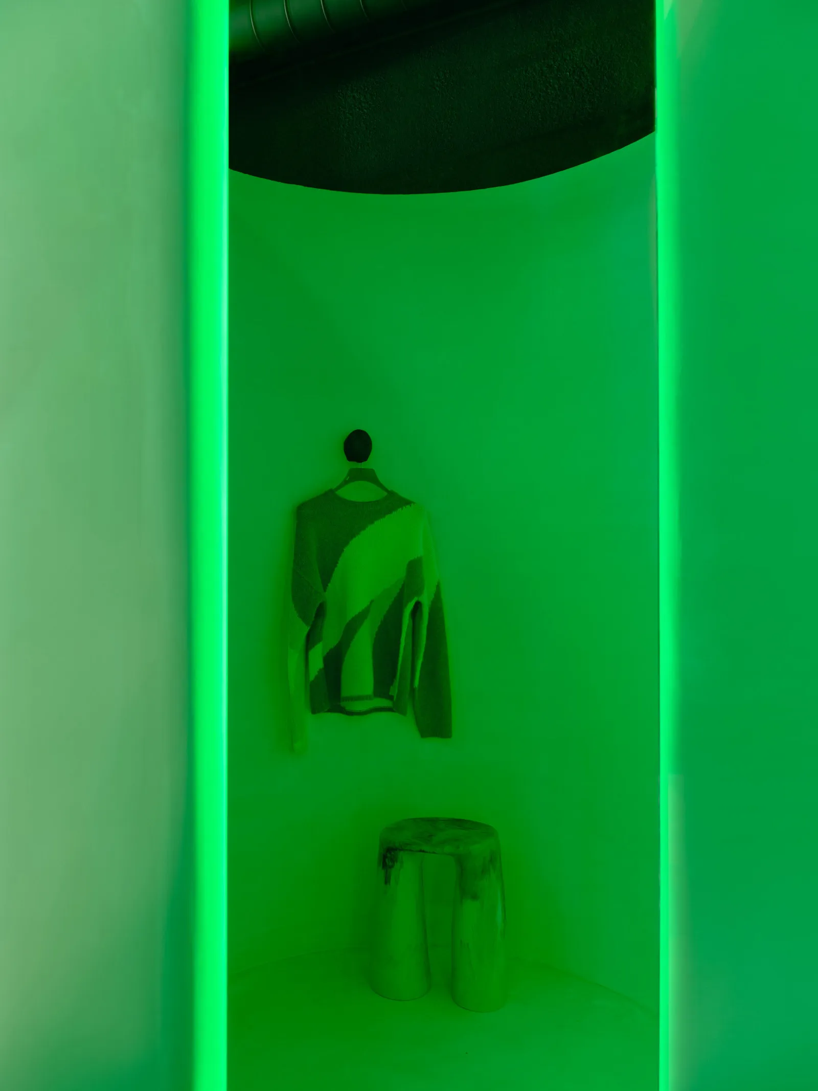 Product display in a retail storefront with a green neon light and sculpture.