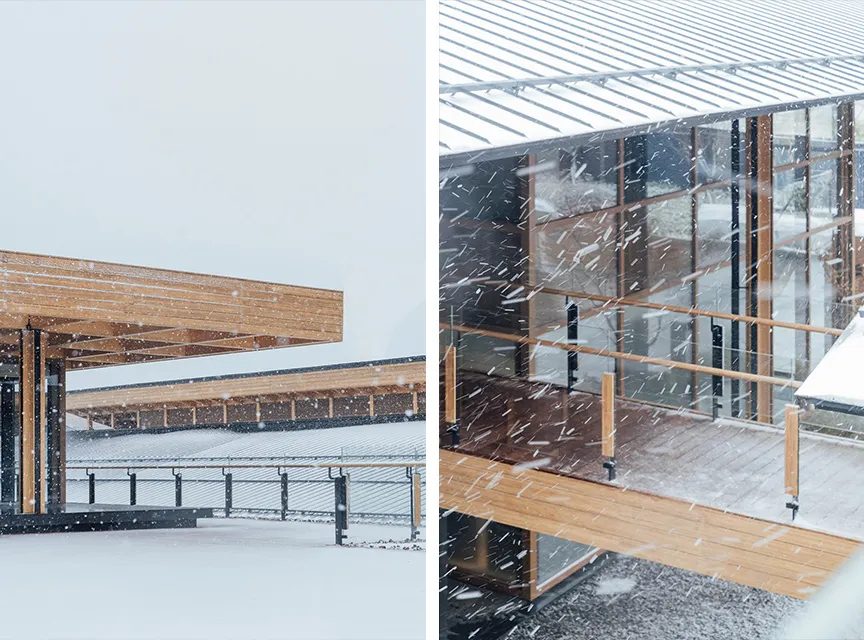 A modern architectural building with a wooden deck during a snowstorm.