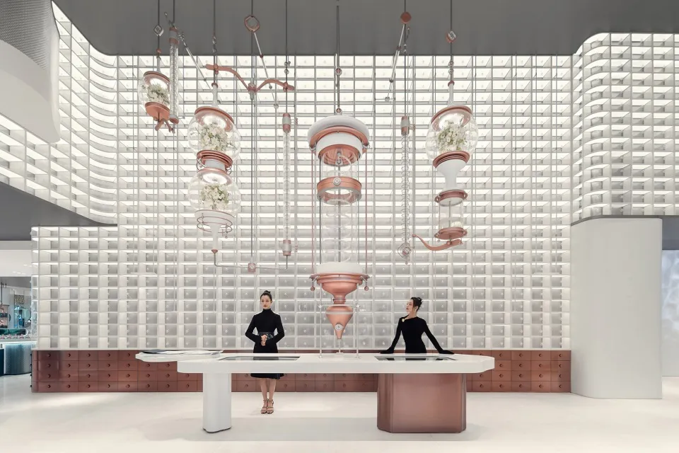 A minimalist retail space featuring white walls, glass and metal fixtures, and hanging glass floral displays.