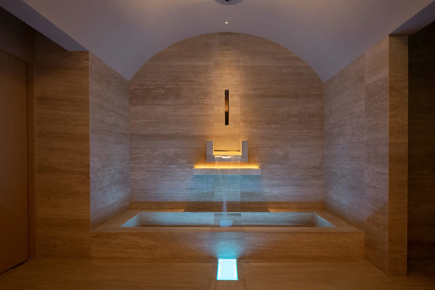 A modern spa interior featuring a concrete water feature with a blue light.