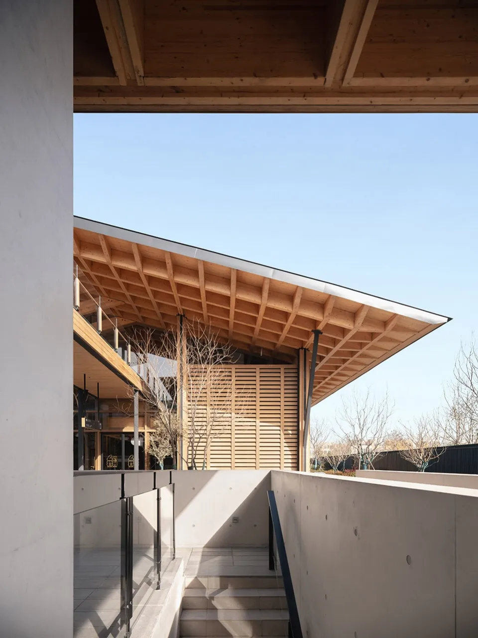 Modern wooden architectural space with a sloped roof and concrete floor.