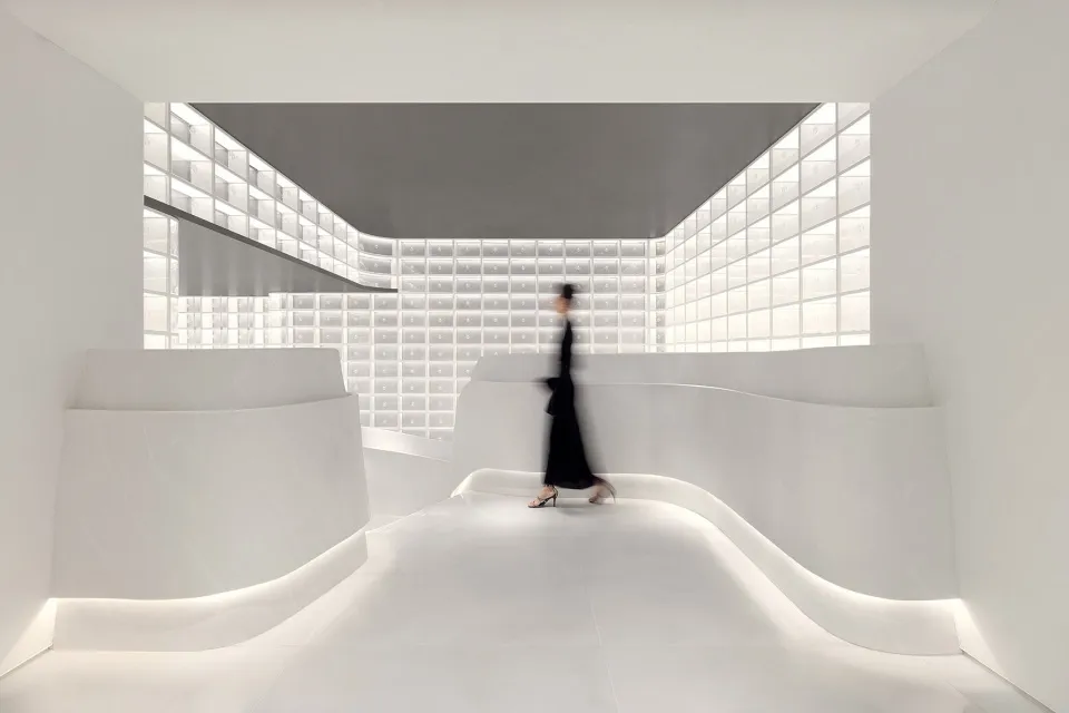 A minimalist interior design with a glass wall and curved white walls.