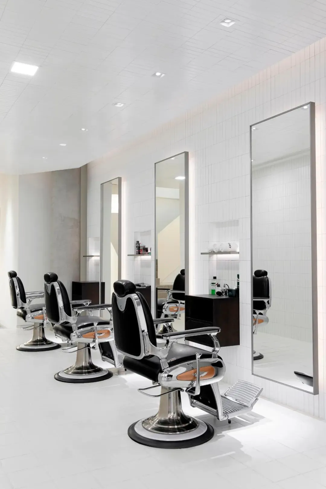 Modern barber shop with metal chairs and mirrors.