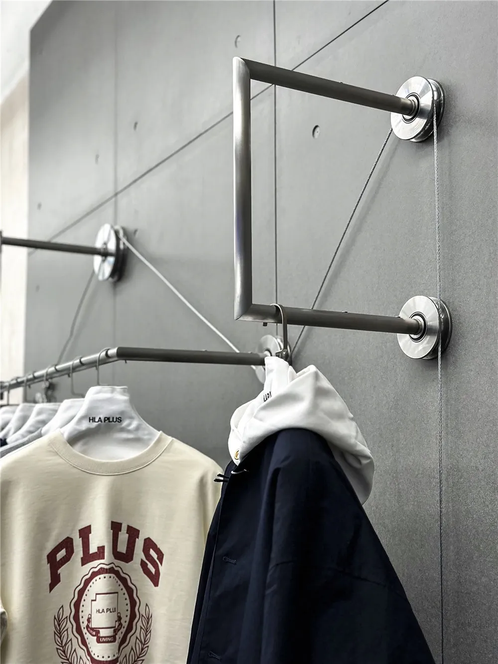 A modern clothing rack with metal rods and a string system for hanging clothes.
