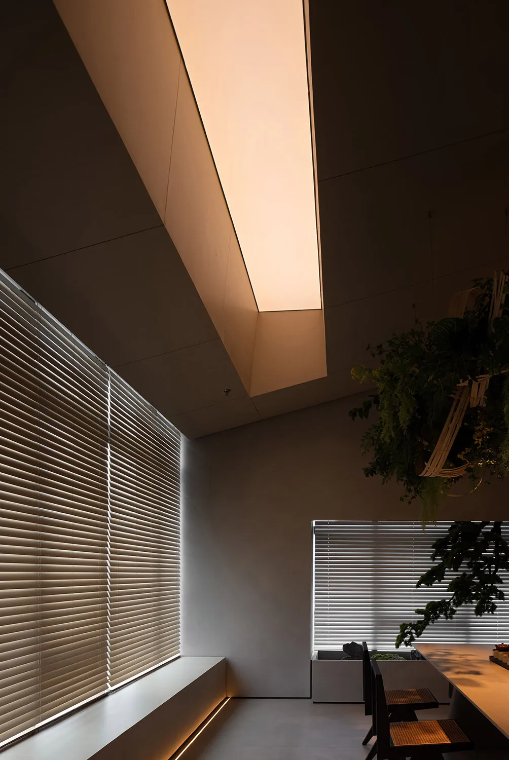 A modern dining room with metallic blinds and green plants