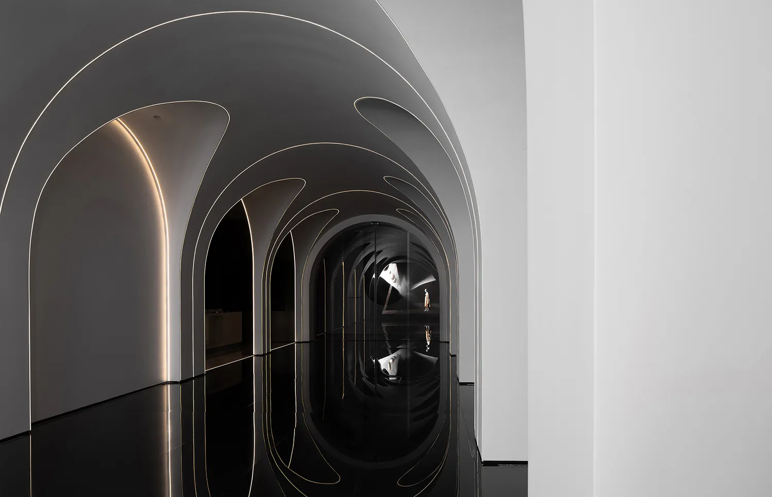 A minimalist, black and white architectural interior with curved glass walls and a reflective floor.