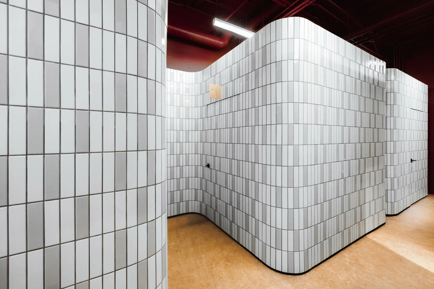 A modern toilet interior featuring white tiles and simple, clean lines.