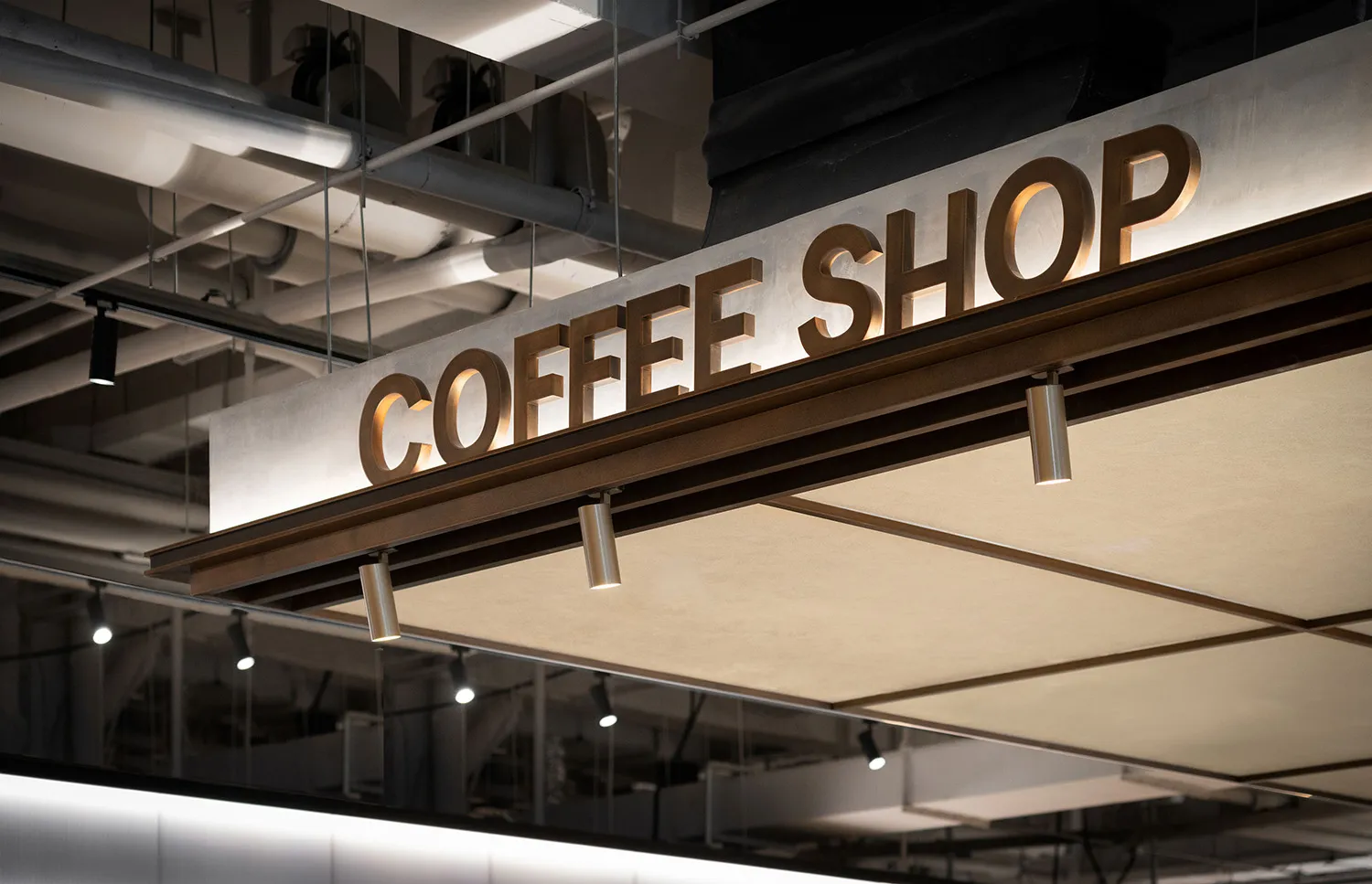 Modern, industrial-style coffee shop signage with metallic cladding.