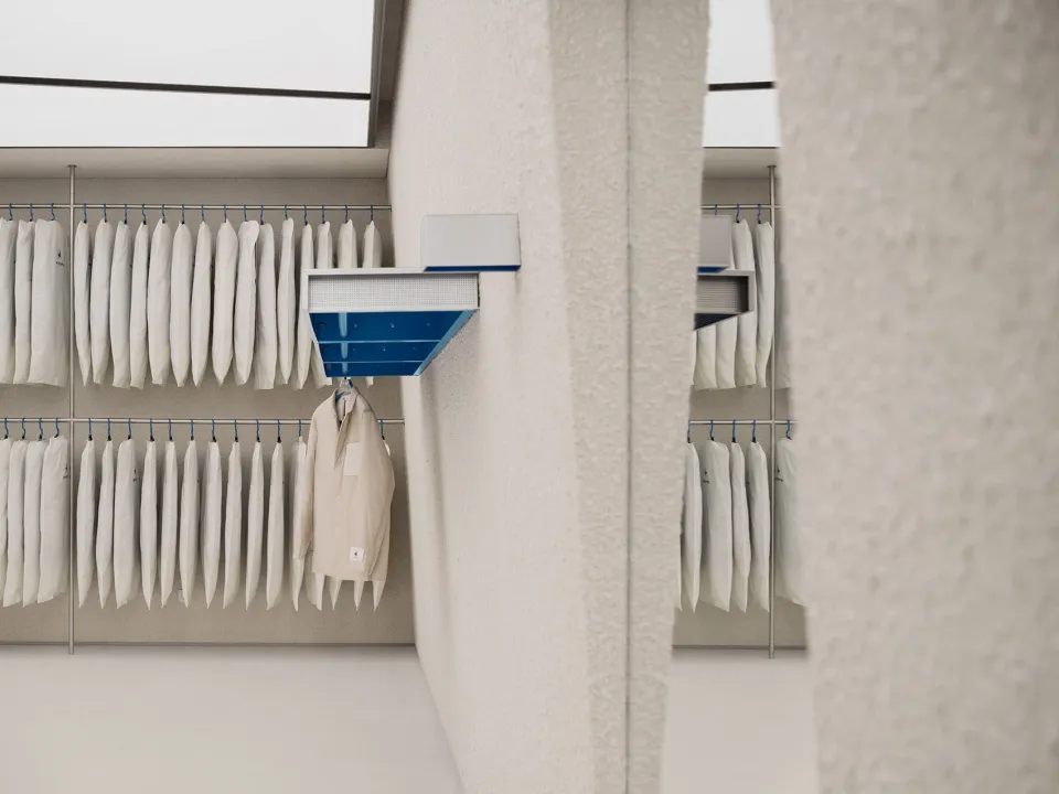 White cloth hangers arranged neatly on a wall-mounted rack.