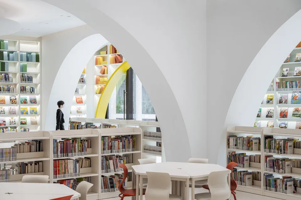 現代圖書館室內,白漆牆面、圓拱造型,以及色彩繽紛的書架。