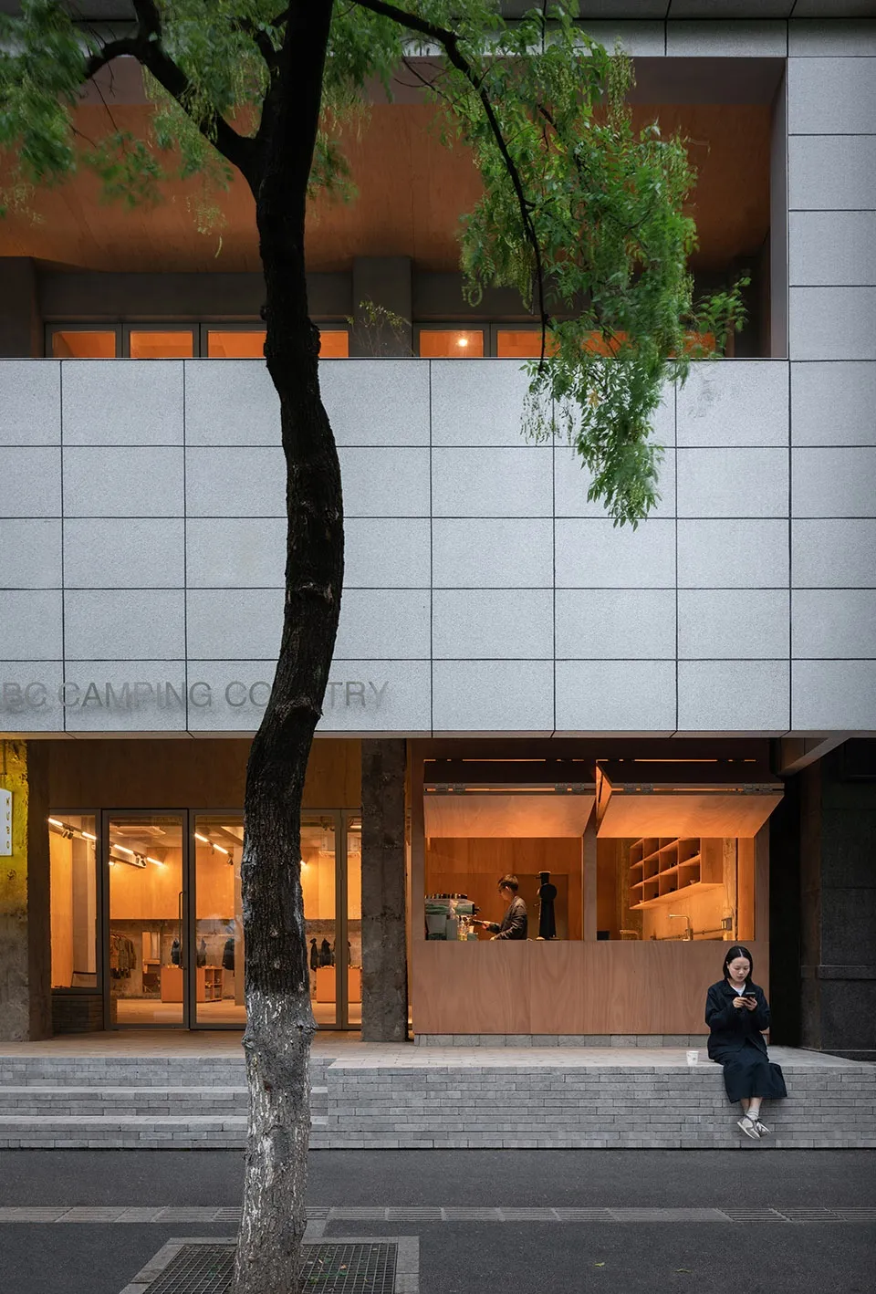 Modern retail storefront with concrete exterior and warm interior lighting.