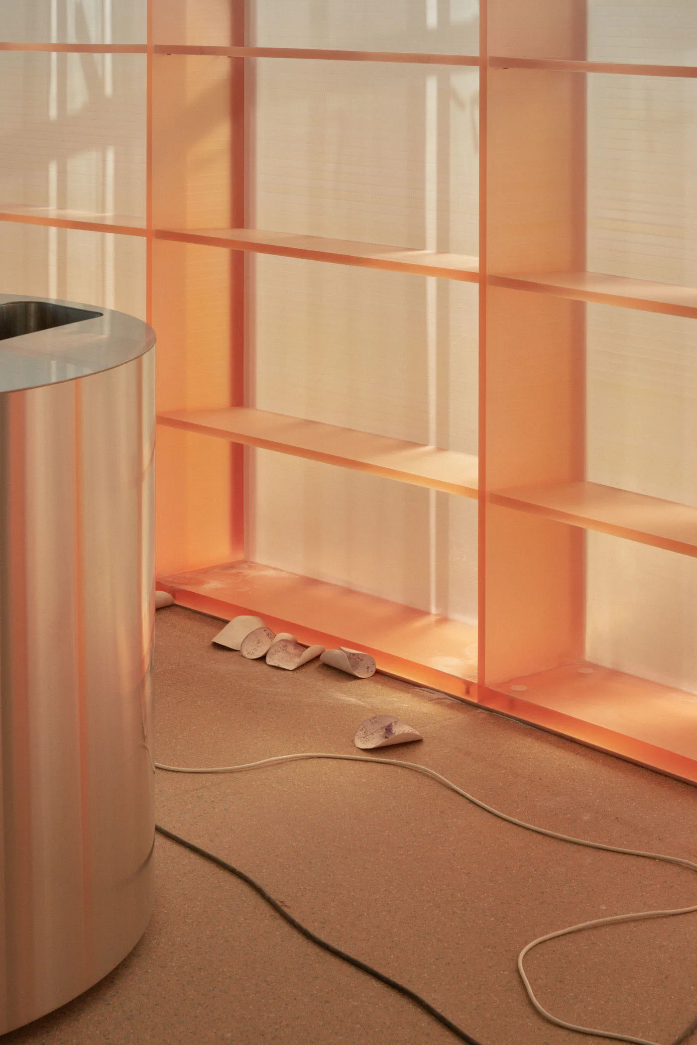 An indoor minimalist design featuring a glass wall and metallic cylinder container.