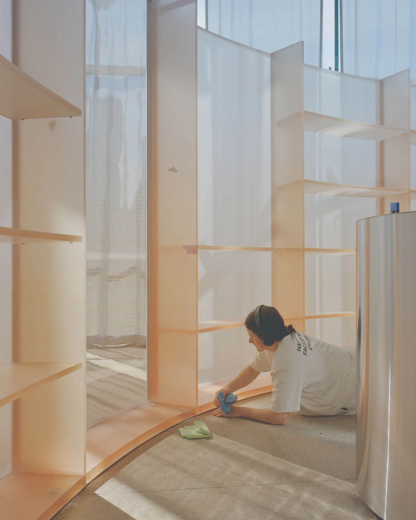 Person cleaning a minimalist interior with white acrylic and copper materials