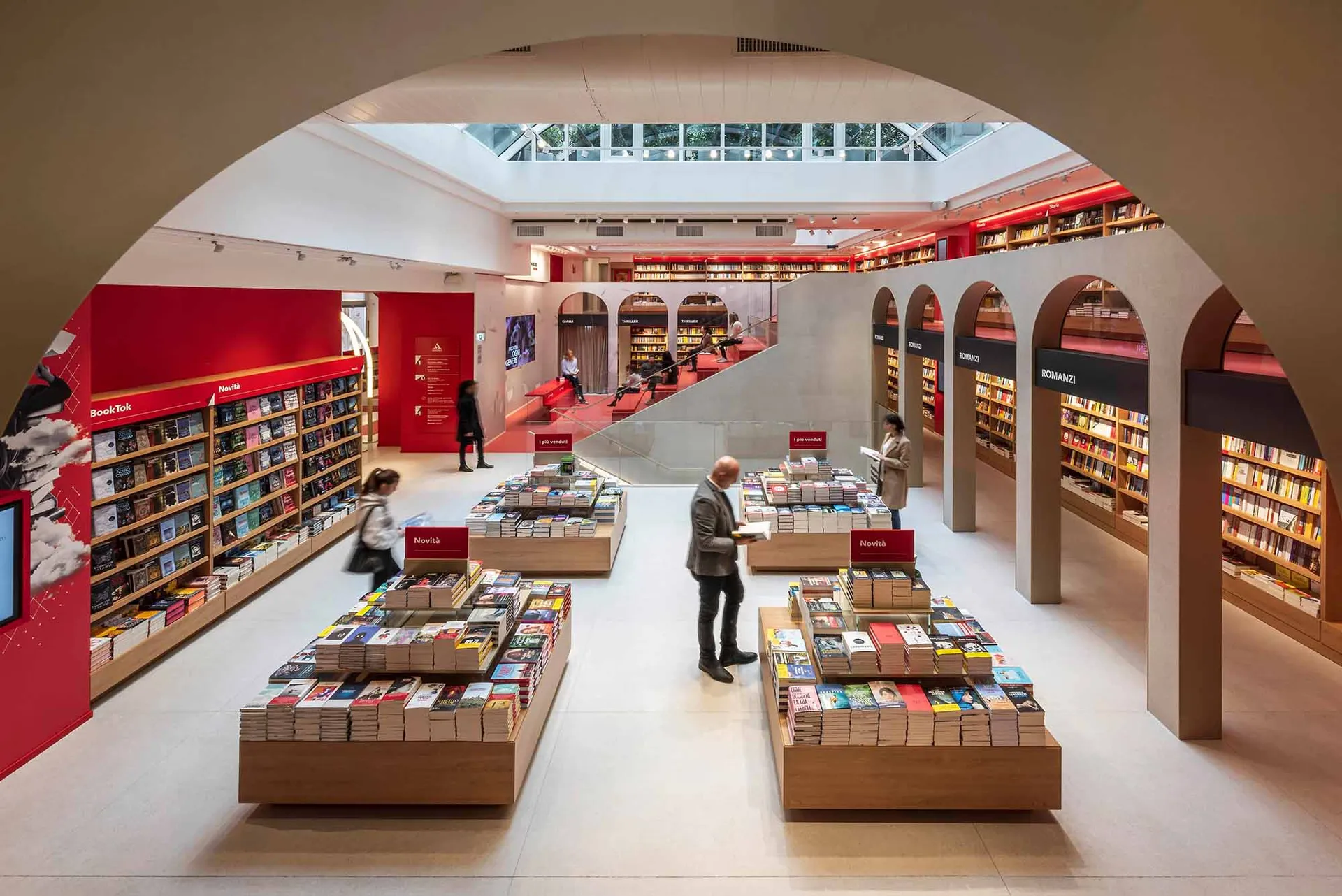 Modern bookstore interior with concrete columns, glass walls, and bookshelves filled with various books.