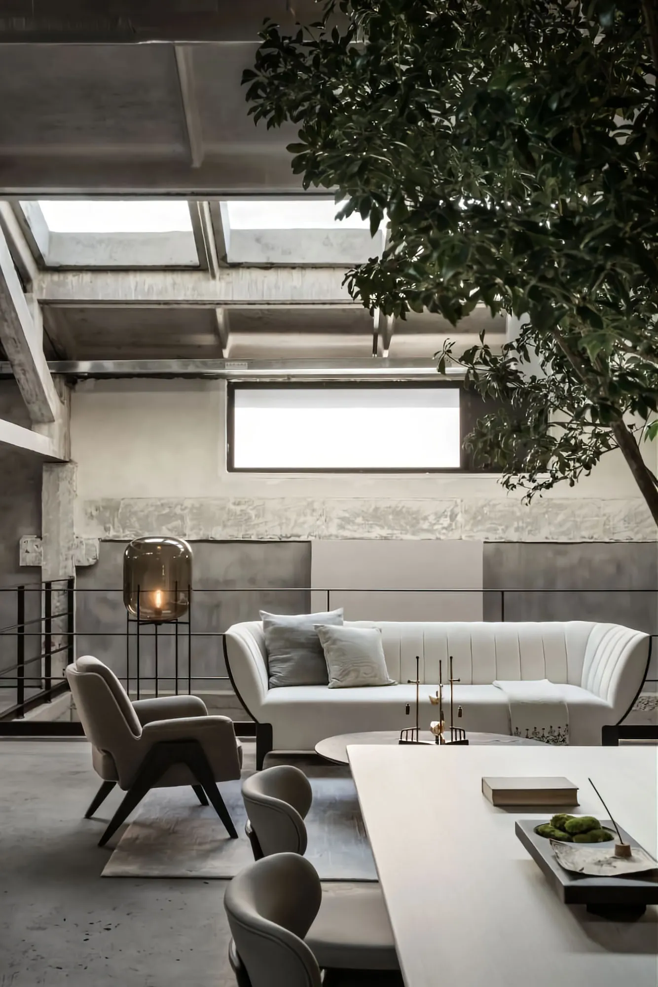A modern living room with a white sofa, a white table, and a concrete floor, under skylights.