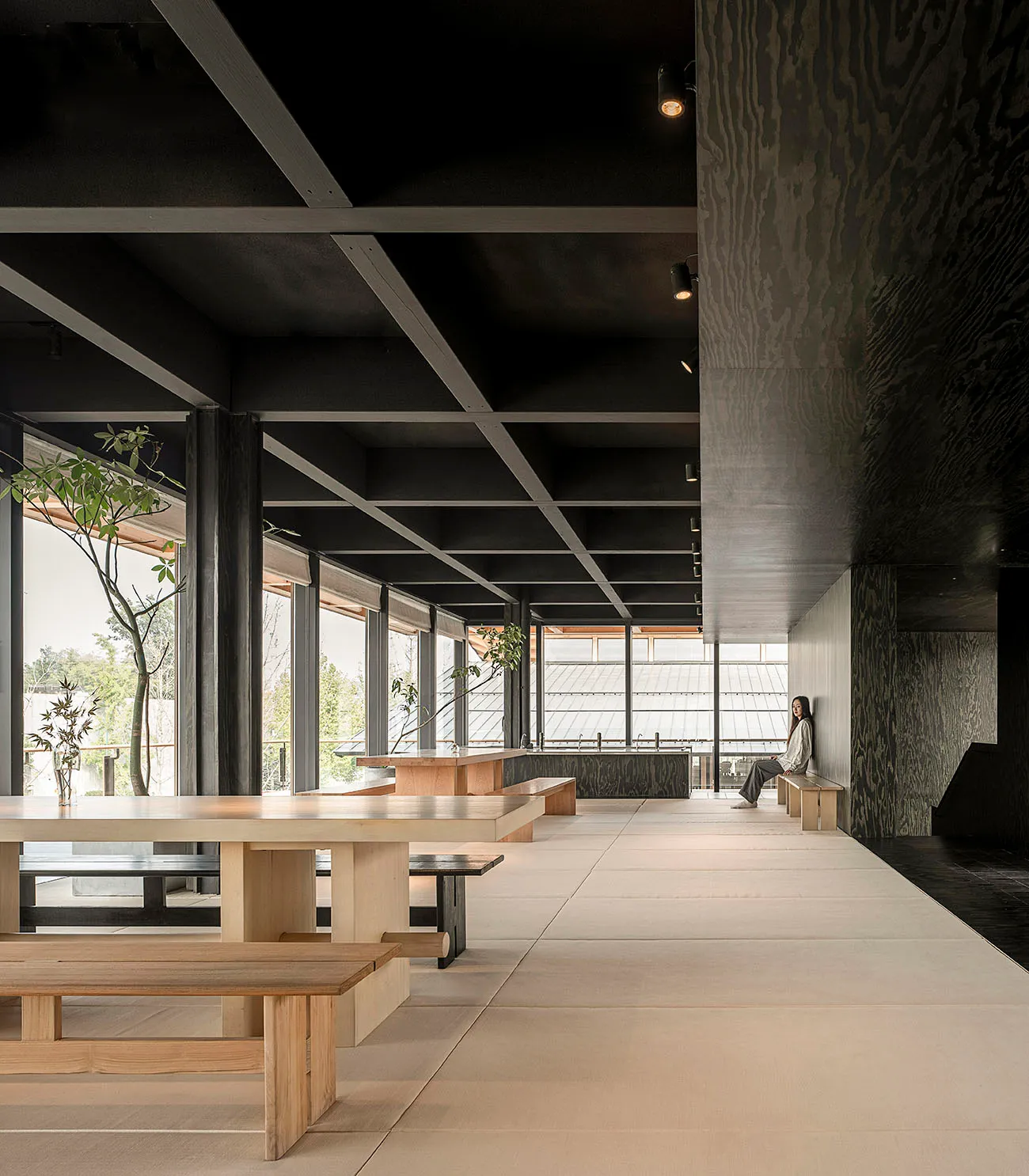 A minimalist restaurant interior with wooden benches and concrete walls.