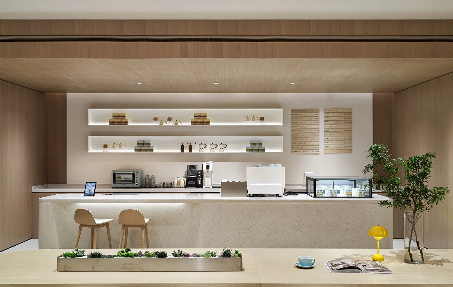 Modern cafe with concrete and wood finishes, featuring a minimalist bar counter with shelves and a table with a plant and boo