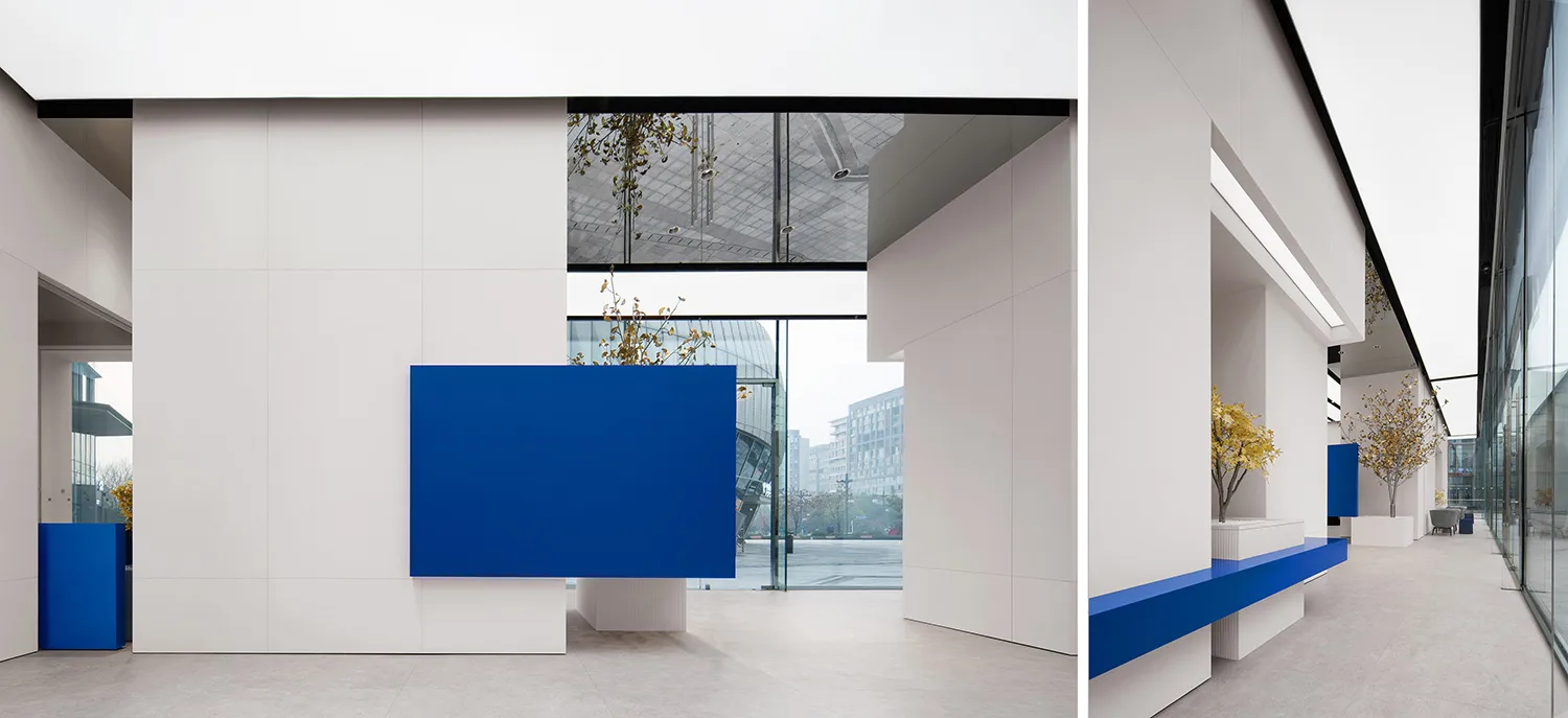 Modern white lobby featuring blue concrete reception desk and glass wall.