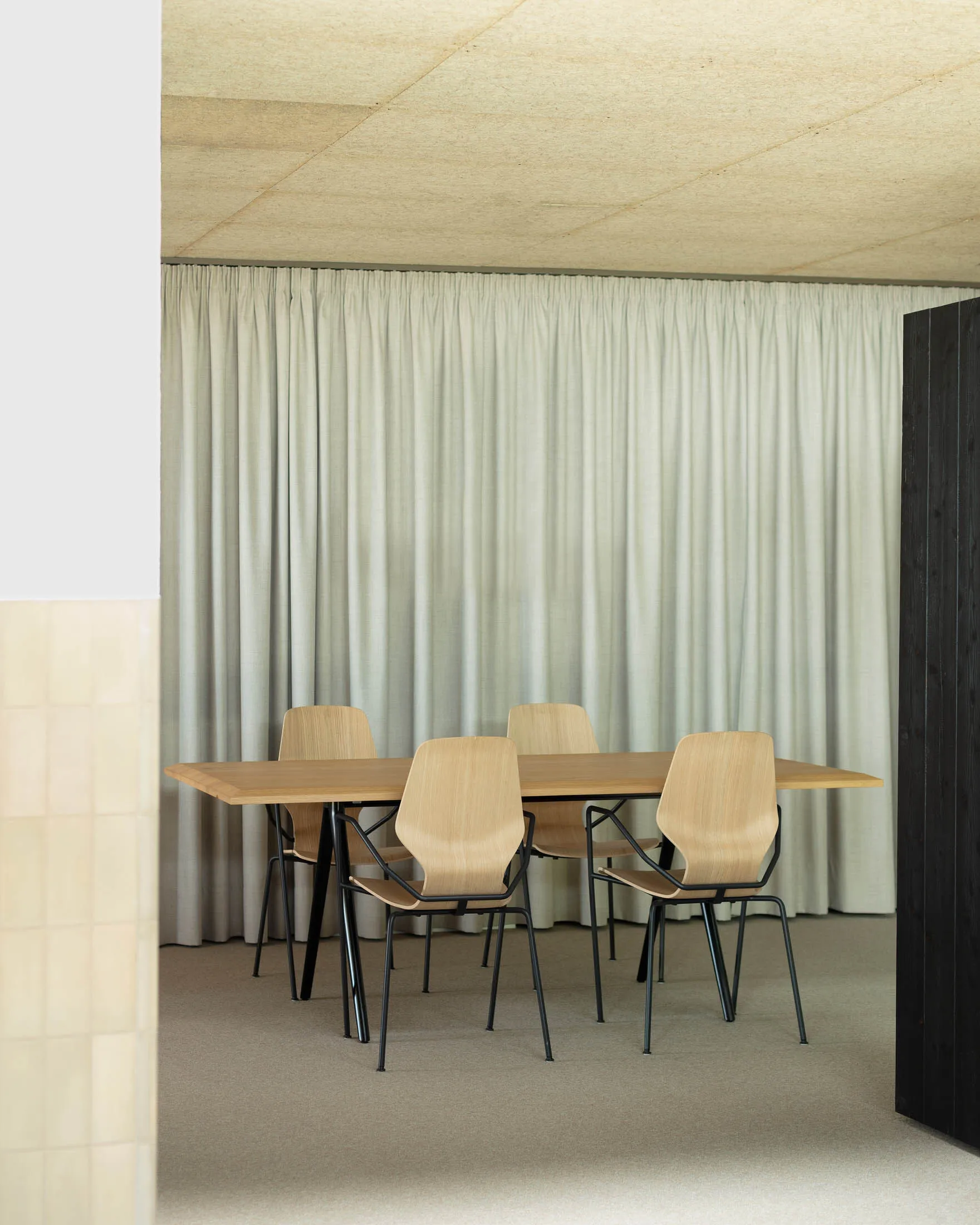 A modern conference room with wooden furniture and a large curtain.