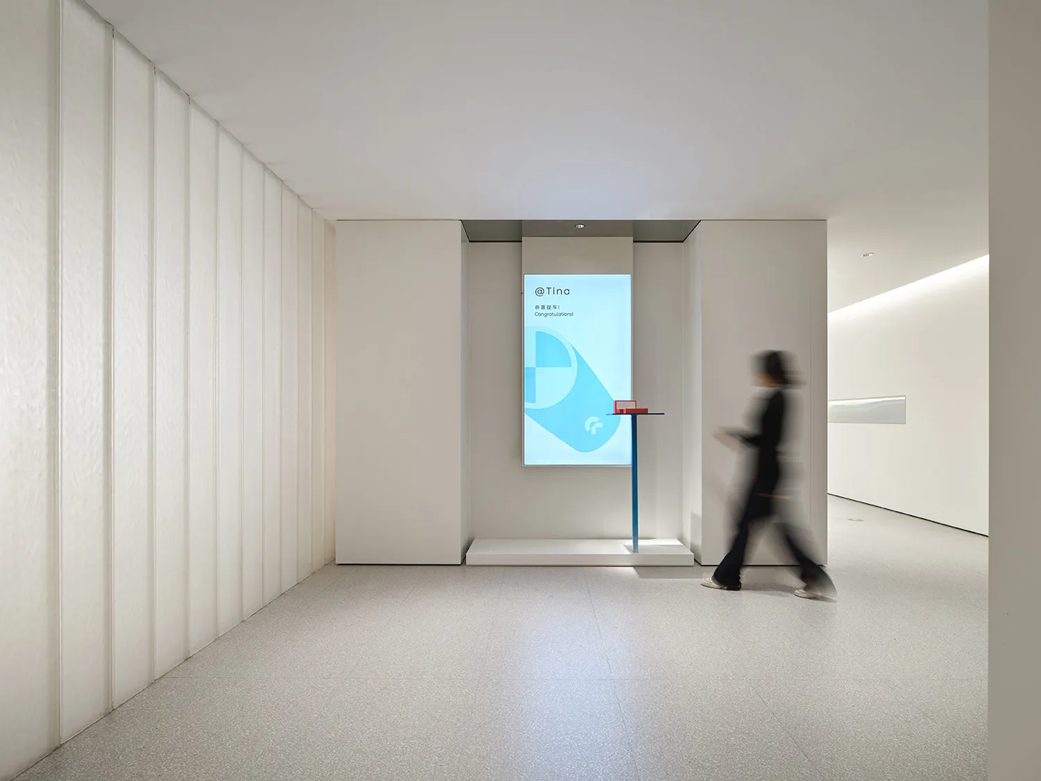 A minimalist interior design with a digital display showing a congratulatory message, illuminated by white lighting and featu