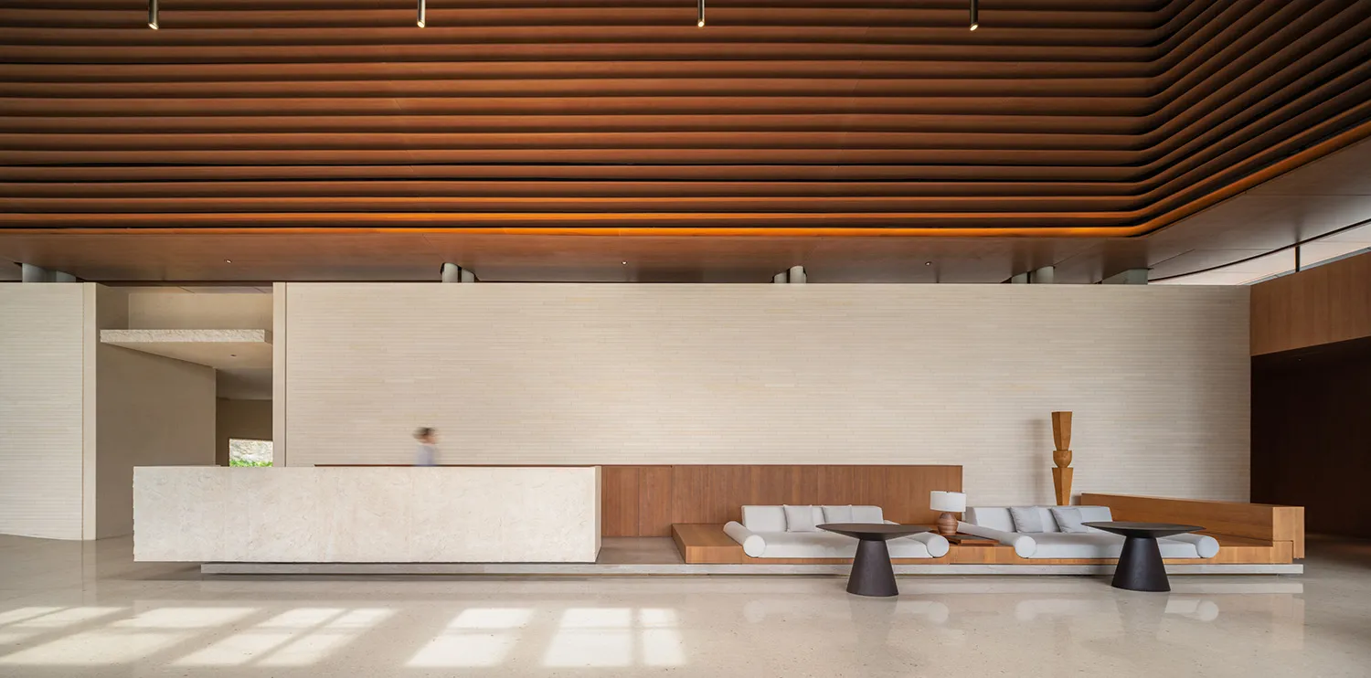 A modern lobby with concrete flooring and wooden accents, featuring minimalist furniture and a sophisticated design.
