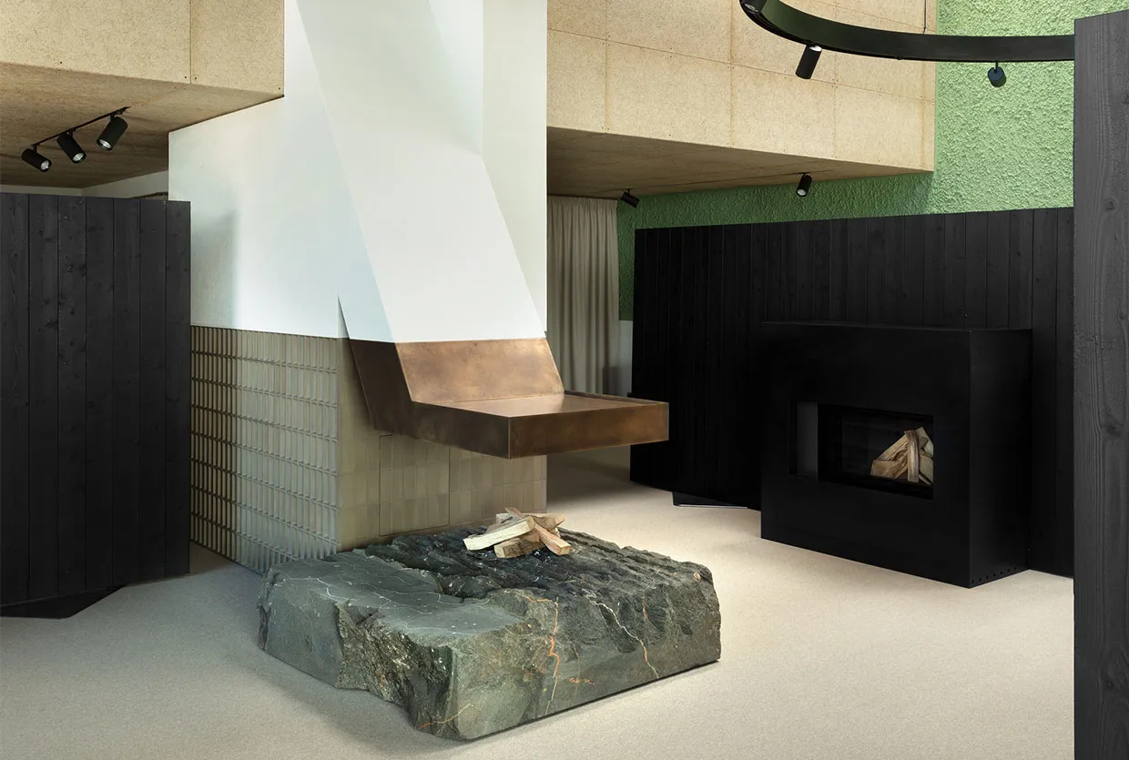 A contemporary living room featuring a metallic desk with firewood underneath and a minimalist aesthetic.