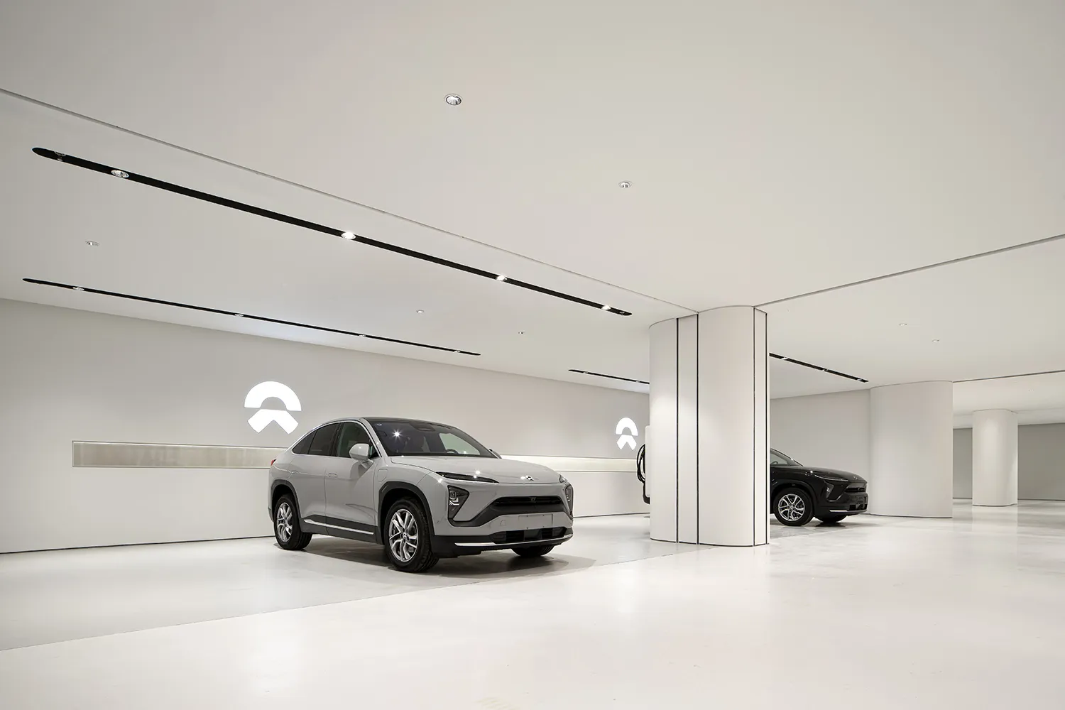 White concrete walls and floor in a modern minimalist car showroom with a sleek, grey SUV on display.