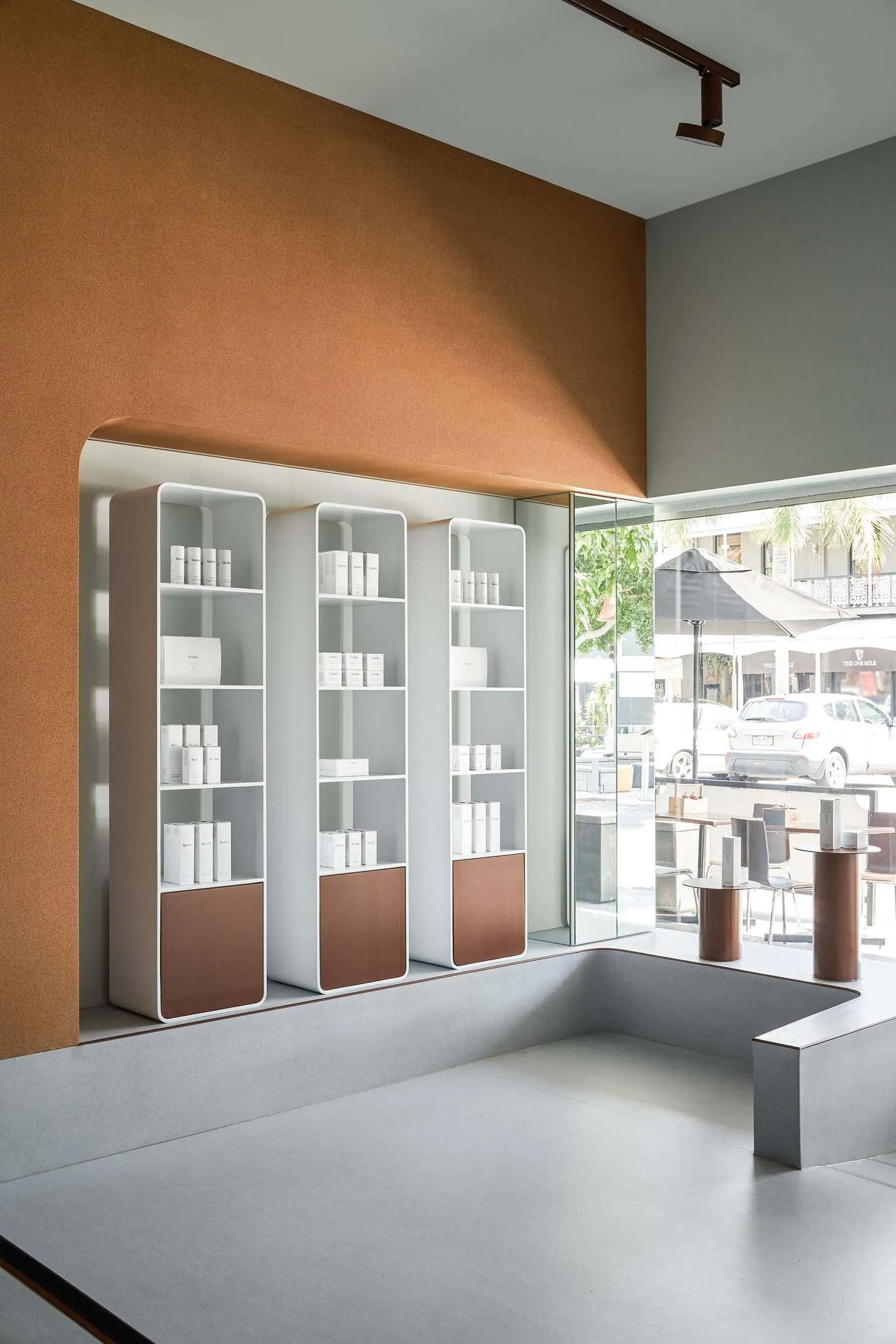 Minimalist retail storefront with concrete walls and glass display shelves.