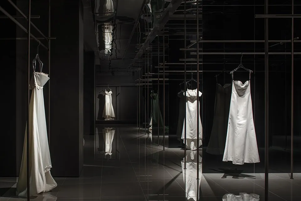 Modern minimalist clothing display featuring sleek metal railings and glass fixtures.