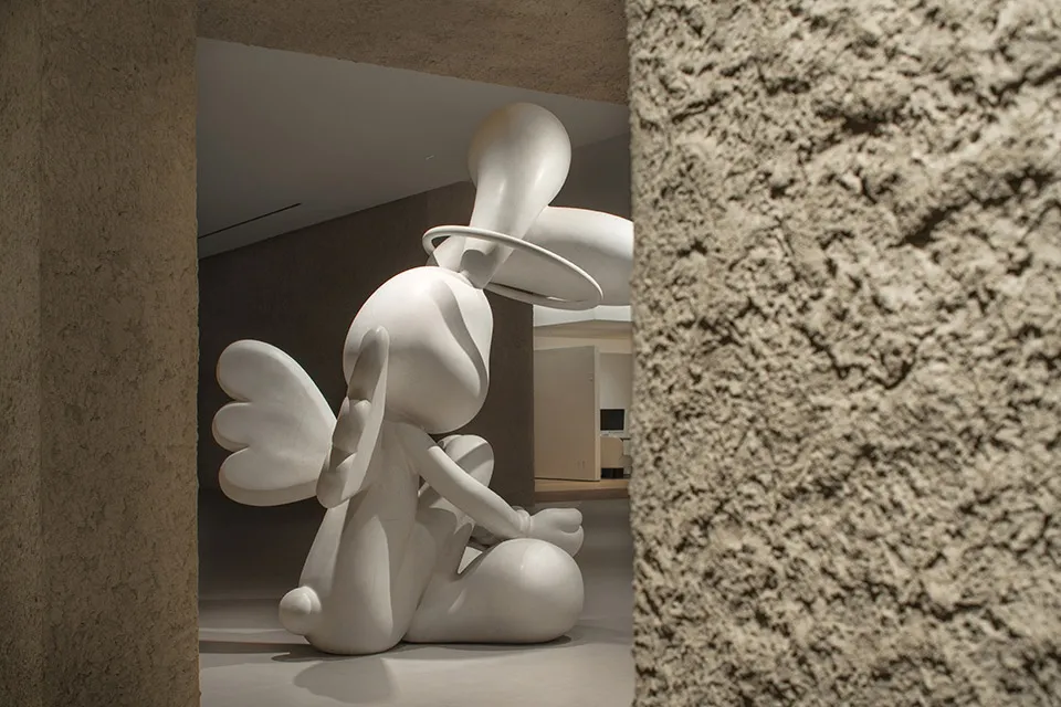 A minimalist plaster sculpture with a halo and wings in a modern design setting.