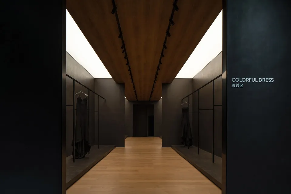 A modern fashion retail space with minimalist design, featuring a wooden floor and sleek, black clothing racks.