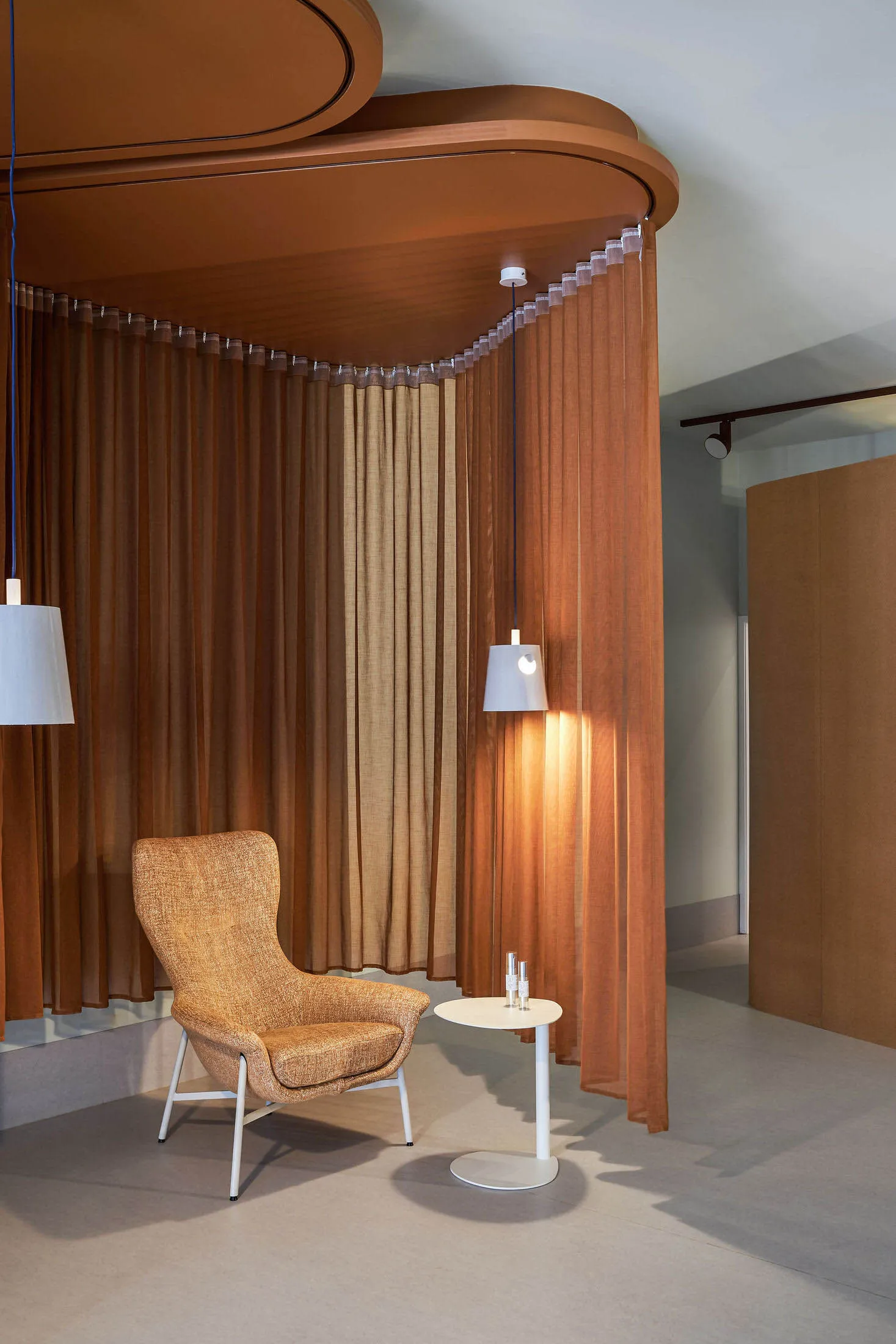 A modern living room featuring a brown curtain installation and a towel chair with a small table.