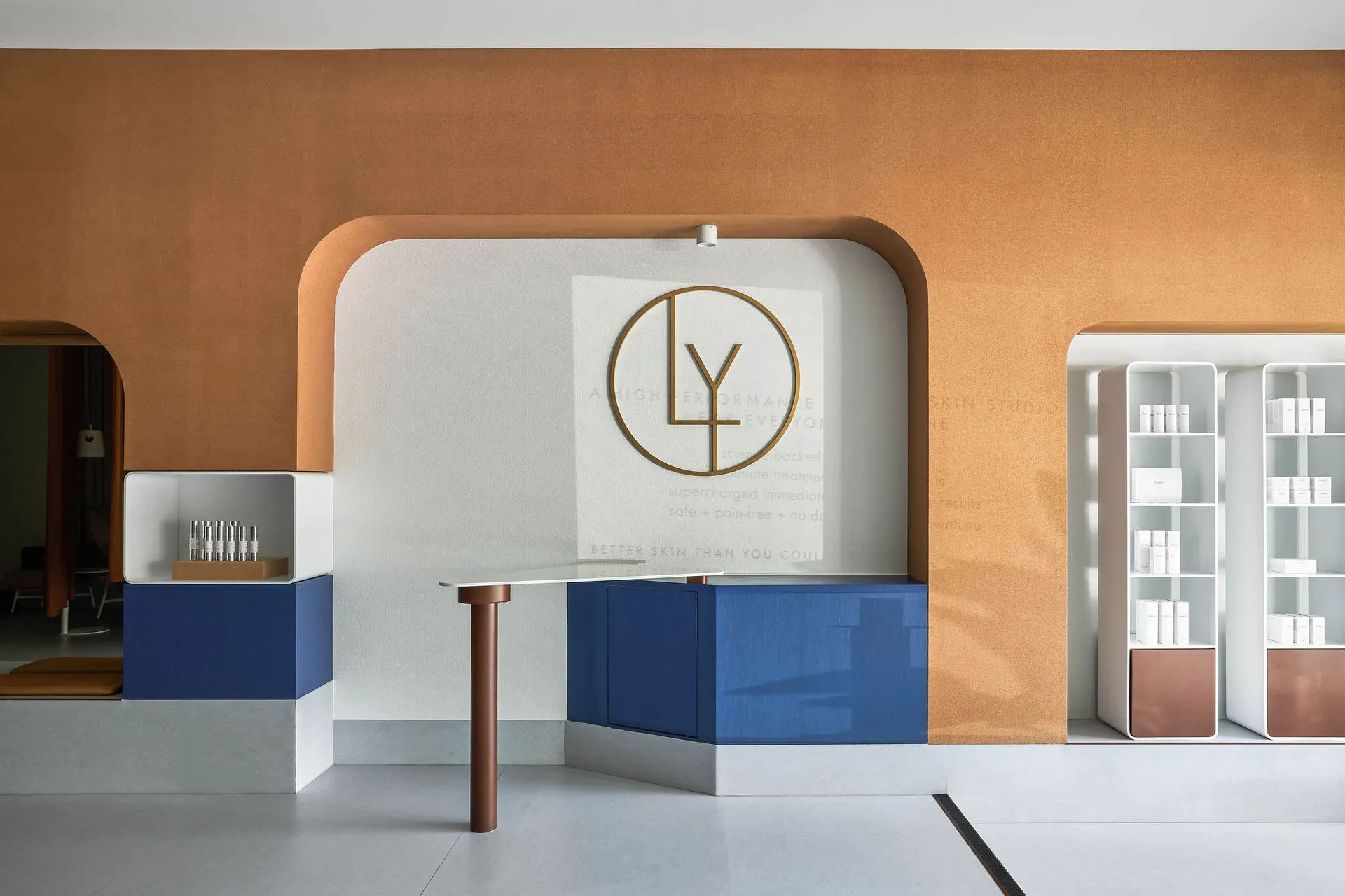 Modern retail shop interior with a blue console desk, glass shelves, and concrete floor.
