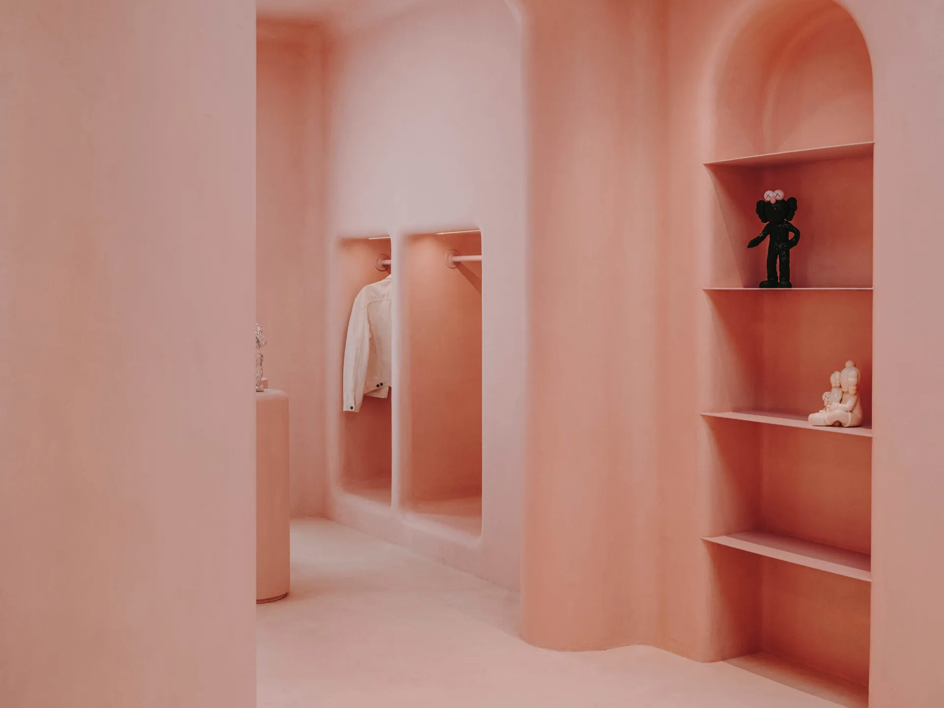 A minimalist clothing retail store with concrete walls and arched doorways.