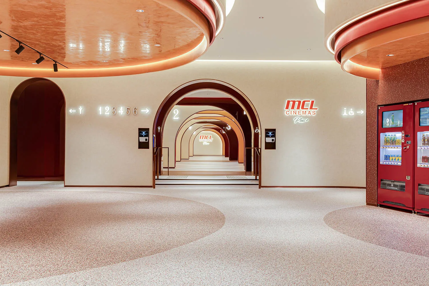 A modern cinema interior featuring polished concrete flooring and curved archways.