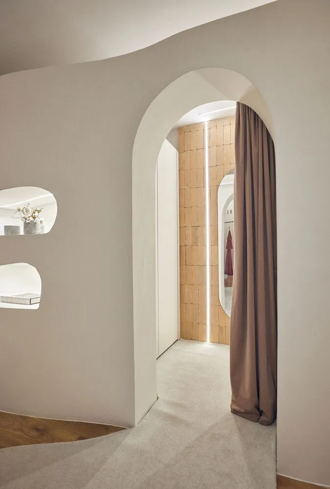 Modern interior with neutral colors, featuring an arched entrance and a curtain.
