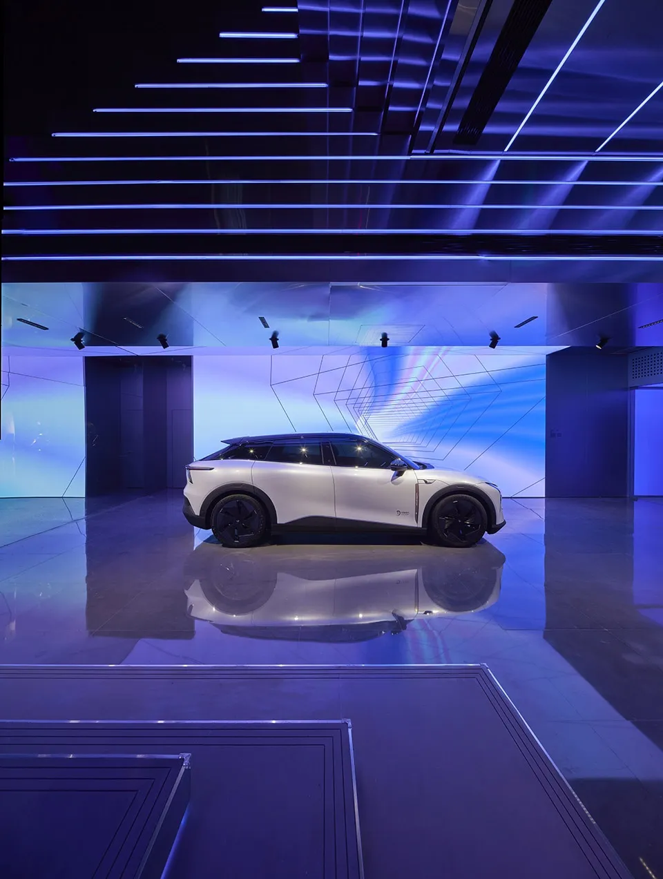 A sleek, white car displayed at a launch event with a futuristic interior and exterior design.