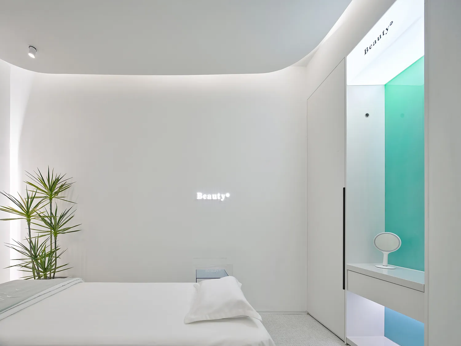 A minimalist spa suite with white walls and furnishings, a green-tinted glass shower, and a neon sign that reads 'Beauty'.