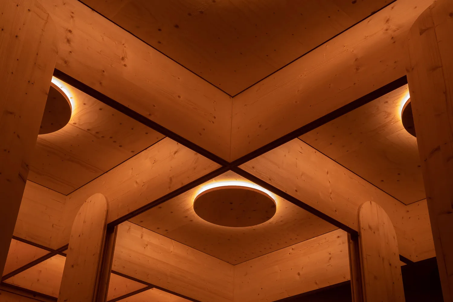 Multiple round wooden lights mounted in a row on a wooden ceiling