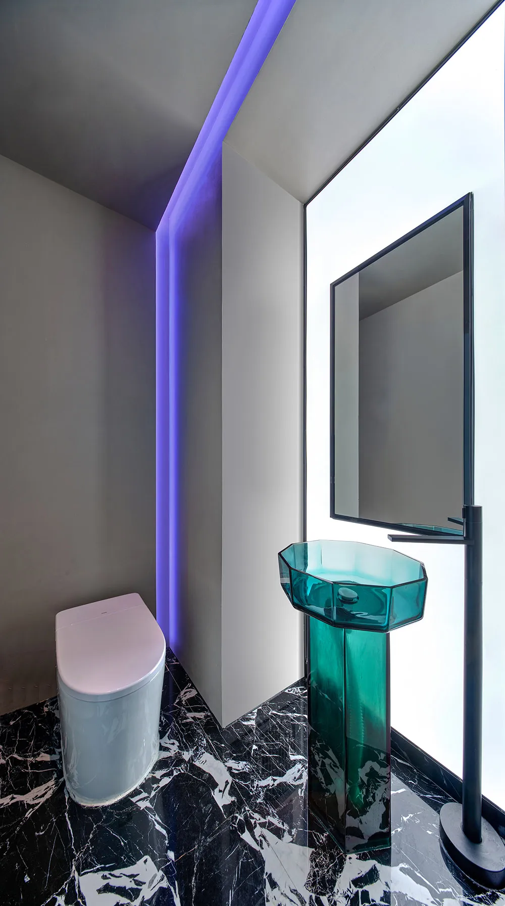 Modern bathroom featuring a transparent glass sink with purple LED lighting on the ceiling, and a black and white marble floo