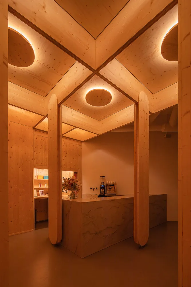 Lobby area of a coffee shop with wooden walls and a circular light fixture.