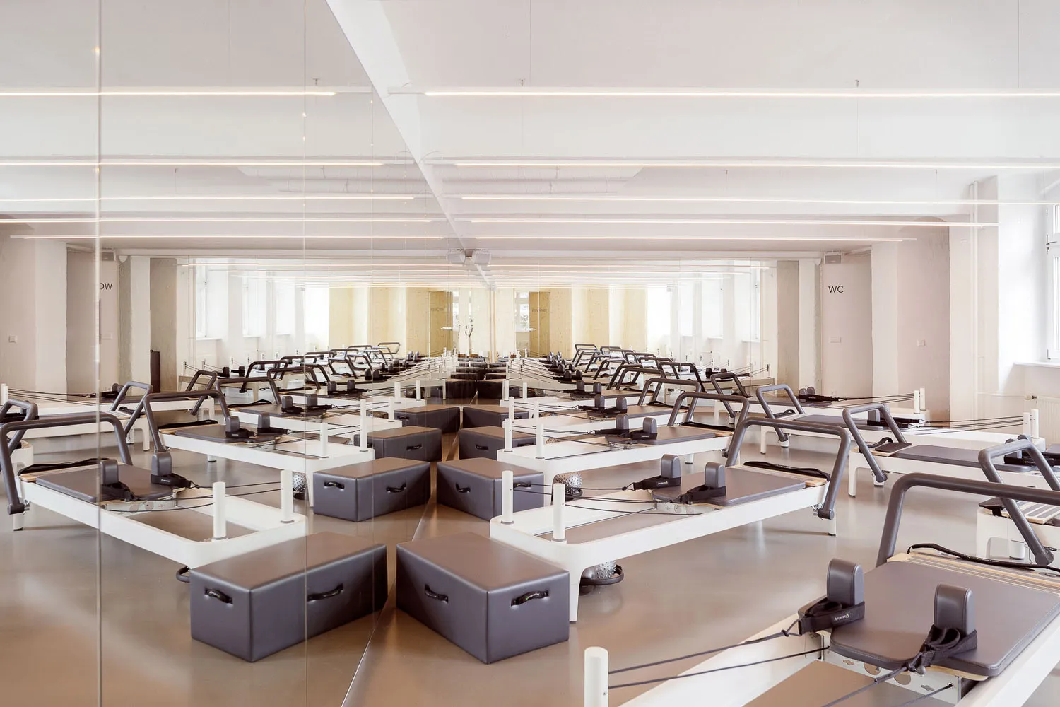 An empty, minimalist indoor fitness center featuring solid-wood flooring andbenches.